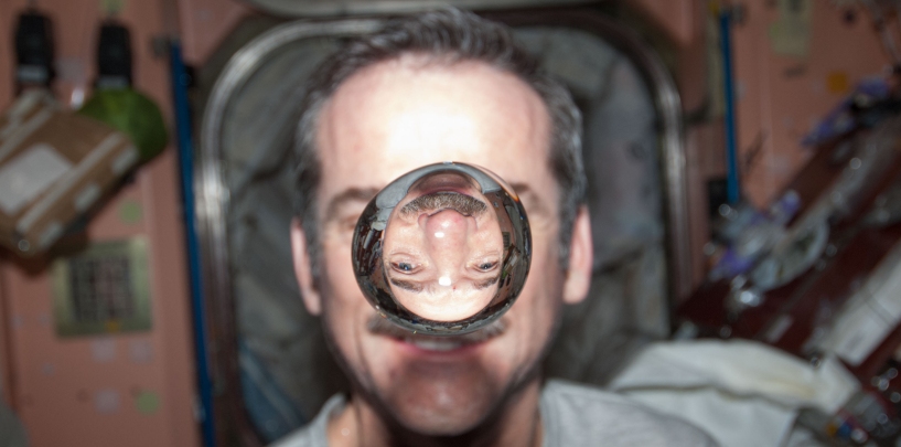 Canadian Space Agency astronaut Chris Hadfield, Expedition 34 flight engineer, watches a water bubble float freely between him and the camera, showing his image refracted, in the Unity node of the International Space Station. (NASA)